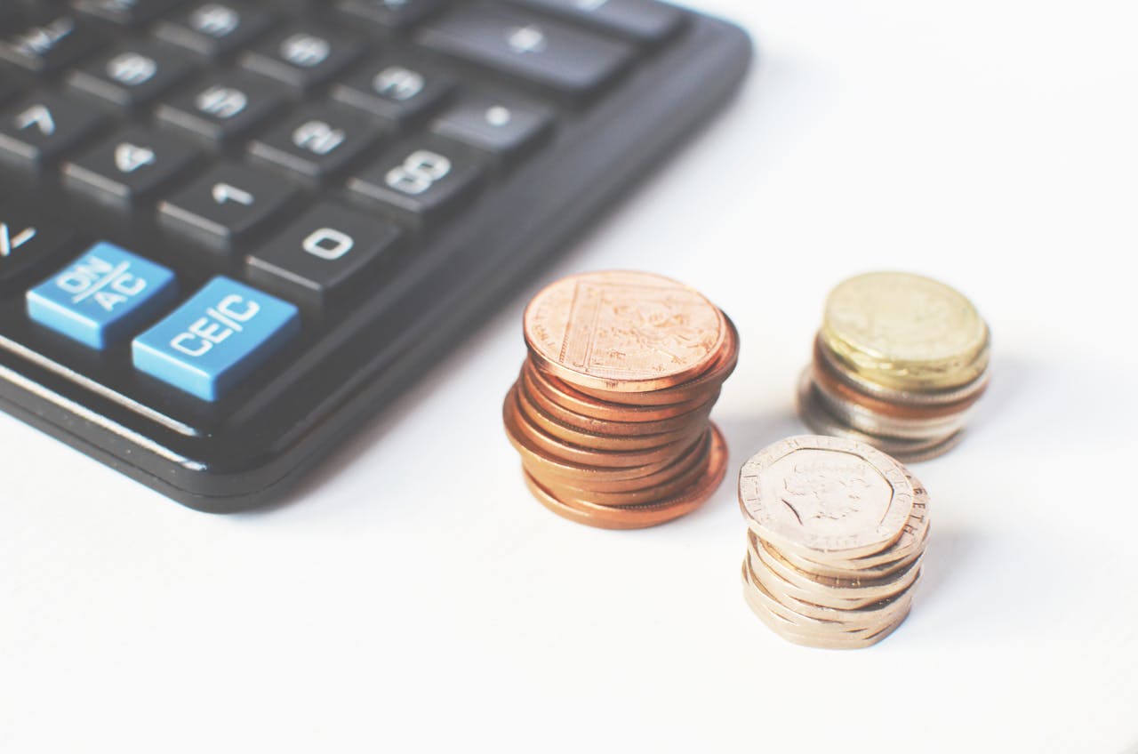 Maison Close-up of stacked coins and a calculator symbolizing financial strategy and budgeting.