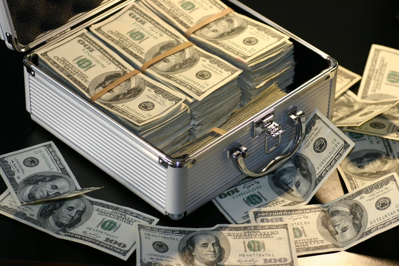 Maison A metallic briefcase full of US dollar bills, symbolizing wealth and investment.