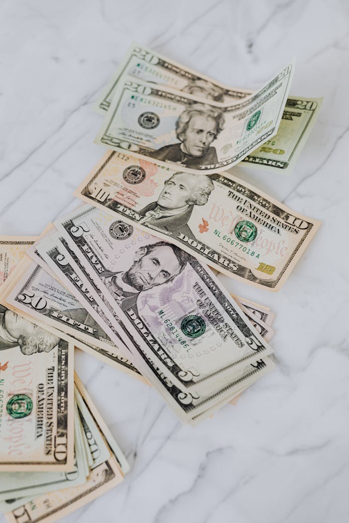 Crisp US dollar bills scattered on a marble surface, symbolizing wealth and finance.